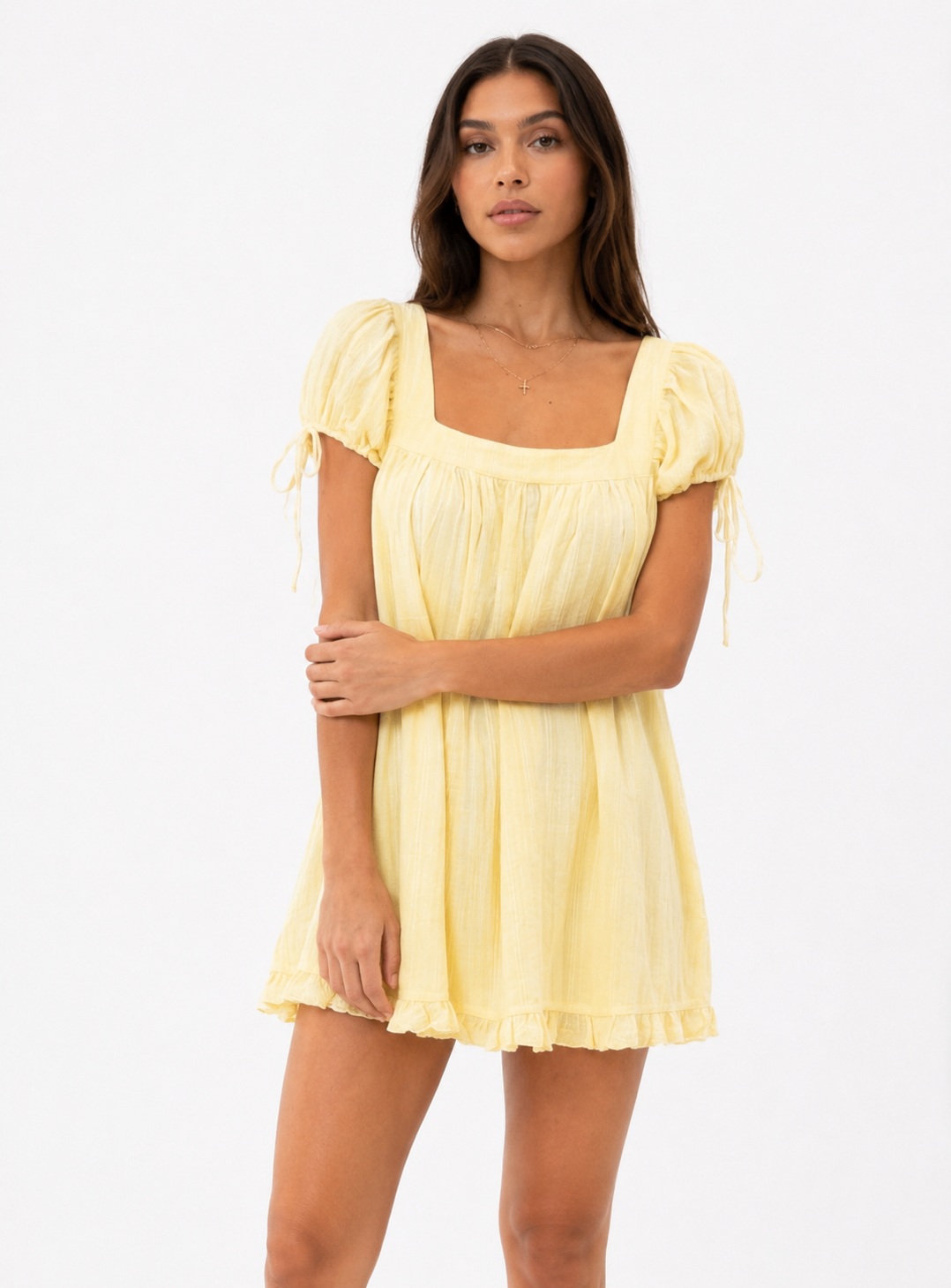 Woman wearing a yellow dress with ruffled sleeves on a white background